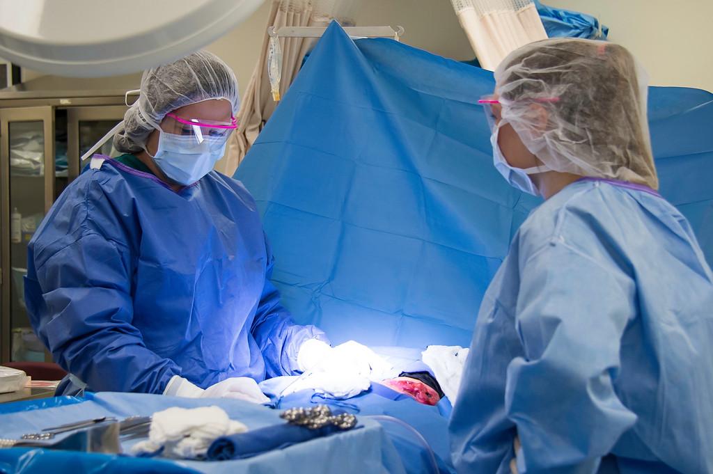 Two nurses in scrubs work in a surgical suite